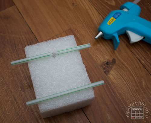 Glue smaller straws onto foam to hold axles